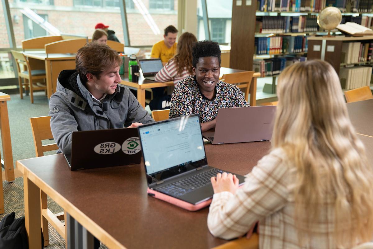 Students with laptops working at a table